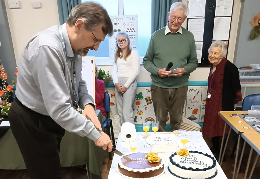 Councillor Paul Tansom Cutting the cake 100 year celebration at Deverell Hall